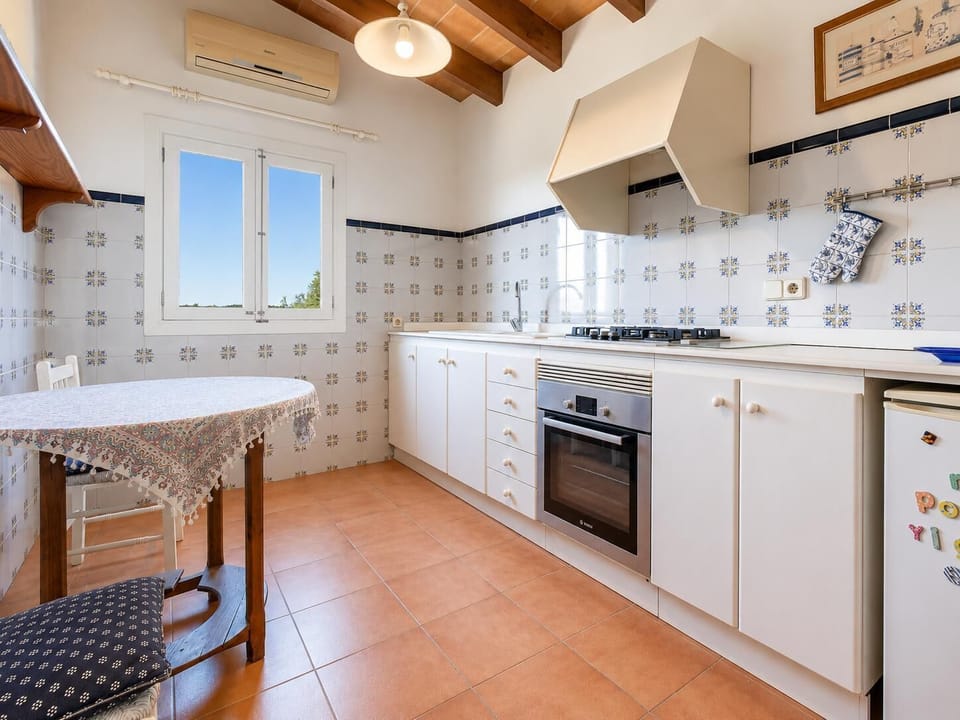 A bright traditional kitchen with patterned tiles, white cabinetry, and warm rustic charm.