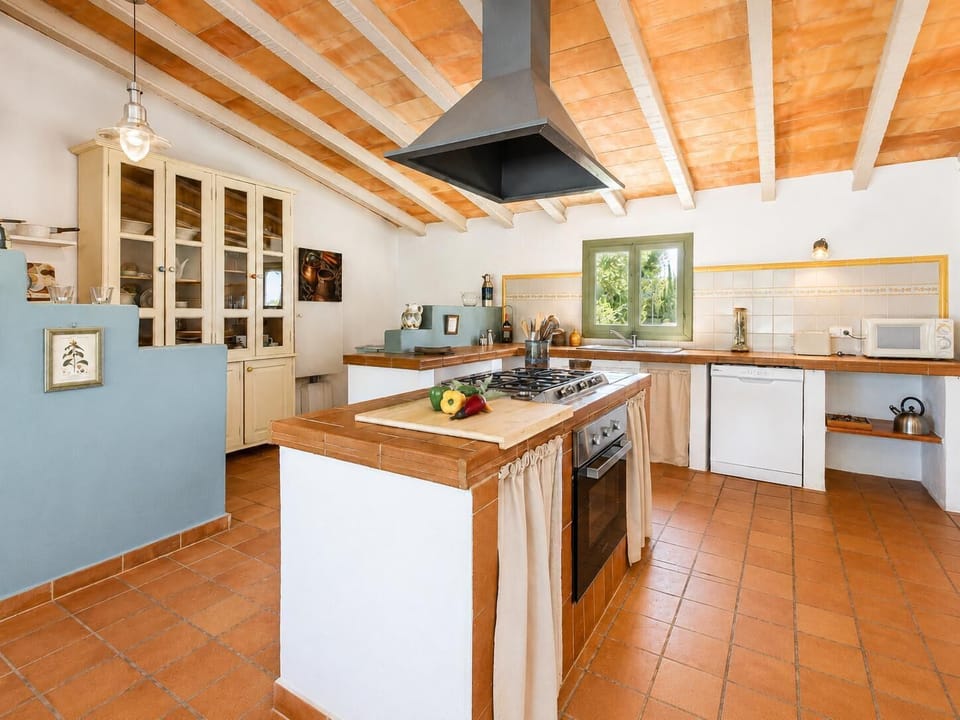 A spacious rustic kitchen with terracotta tiles, a central island, and warm country charm.