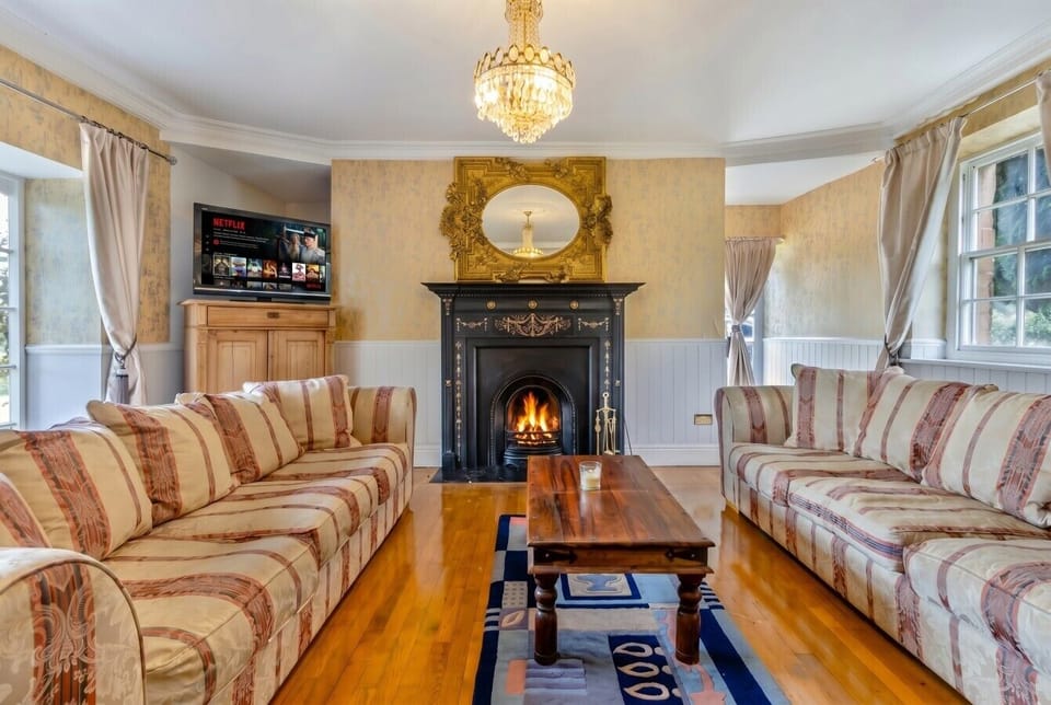 Elegant lounge with crackling fire, Netflix and grand gilded mirror