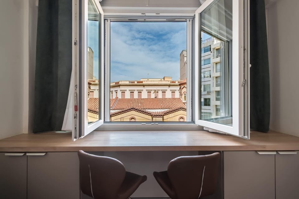 Openable windows frame city rooftops and blue skies, bringing daylight, airflow, and an uplifting urban atmosphere.