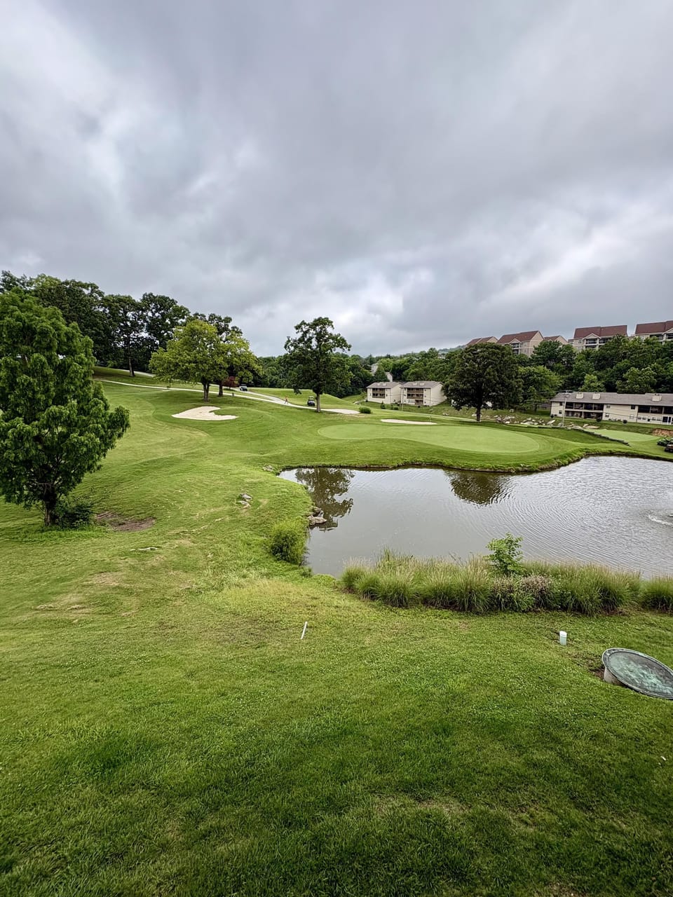 View from the condo shows a green golf course with sand traps, a water hazard, and residential buildings in the distance.