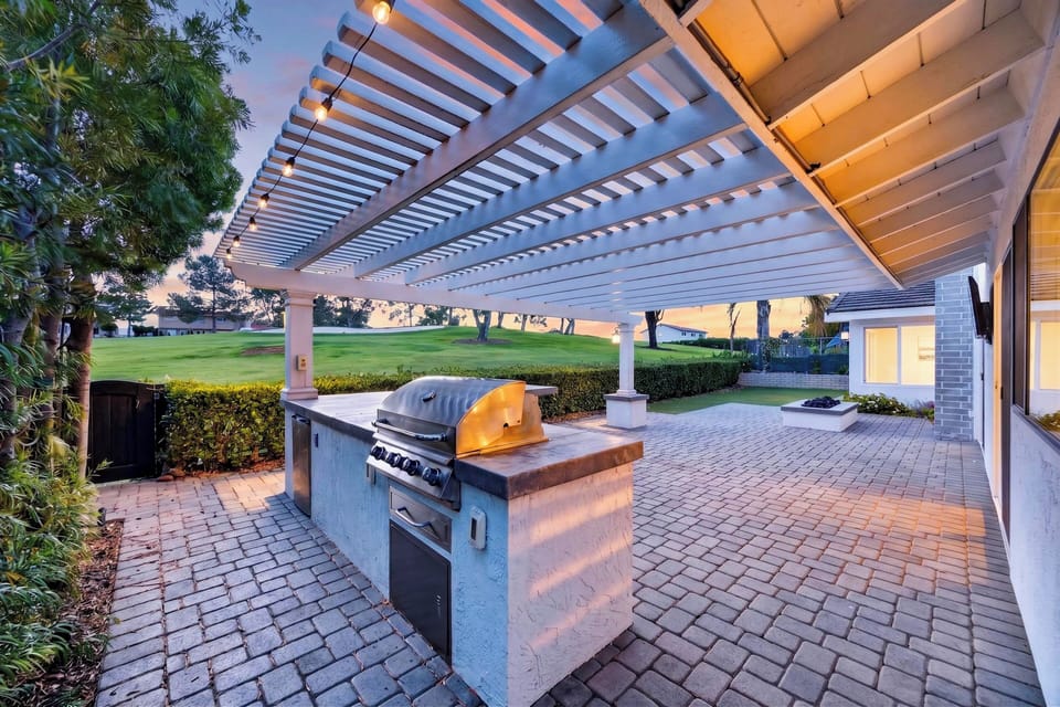 Experience ultimate outdoor living under a magnificent custom pergola, complete with a built-in BBQ island and string lighting.