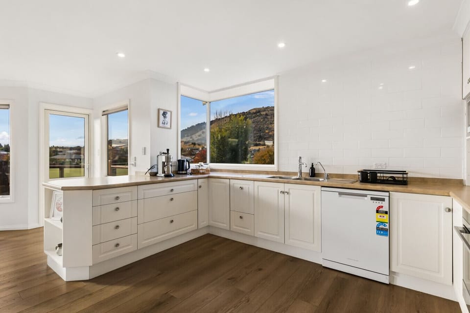 Fully equipped white kitchen with generous bench space and garden views