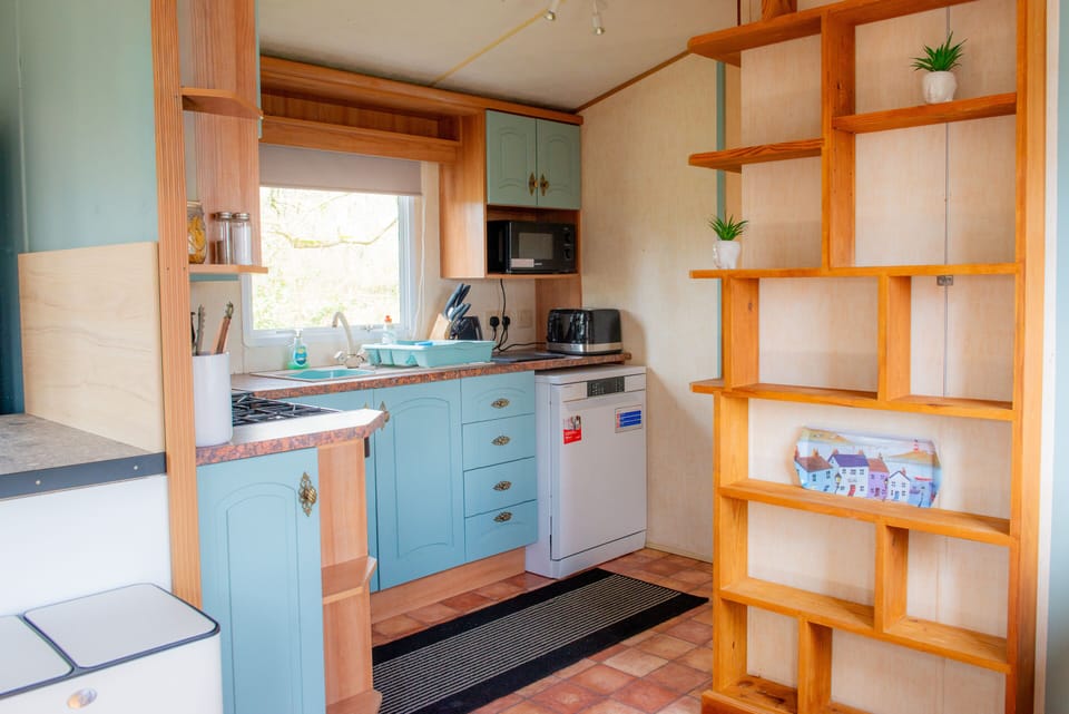 A fully equipped kitchen featuring a dishwasher, gas hob, oven, toaster, kettle, fridge freezer, and ample storage space.
