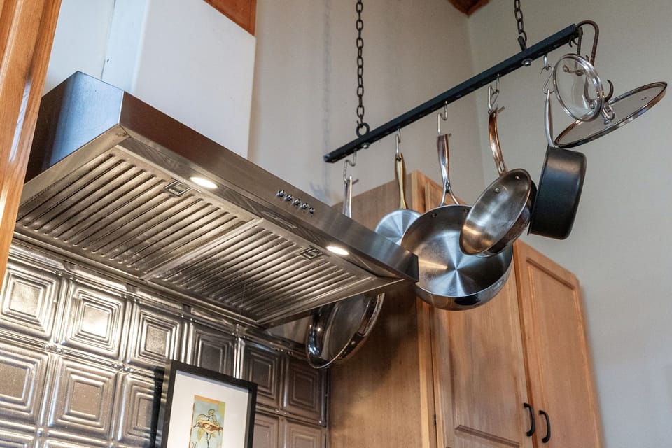 Thoughtfully stocked kitchen with hanging cookware and rustic cottage charm.