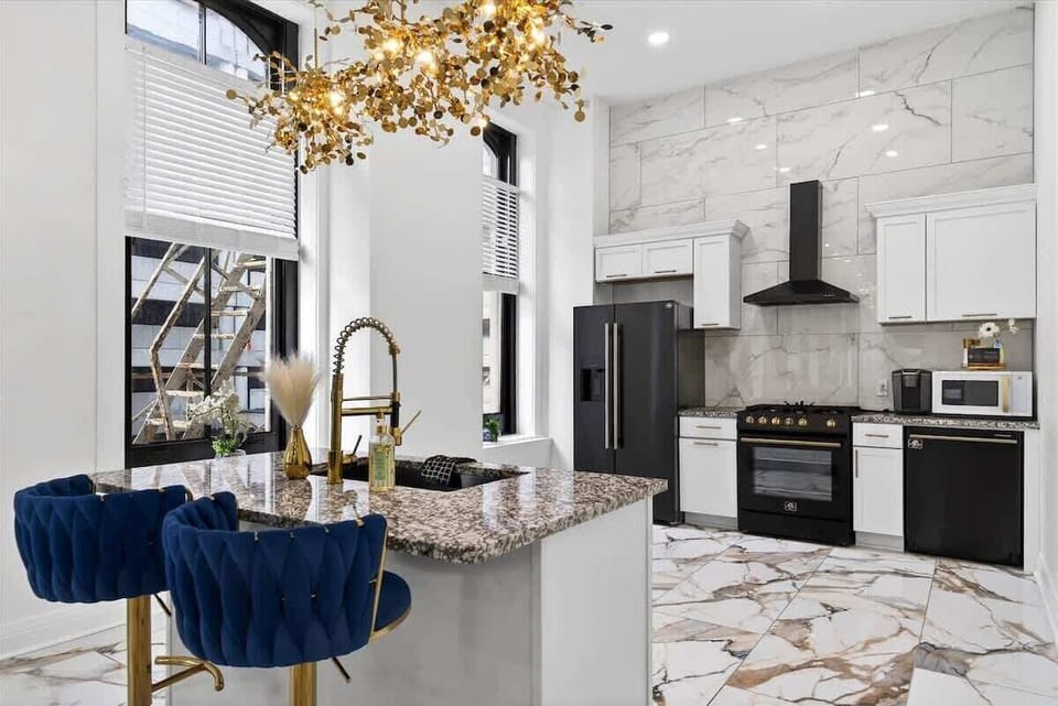 We installed high-end black stainless steel appliances including a gas range and french door fridge. The gold cabinet hardware pops beautifully against the white cupboards.