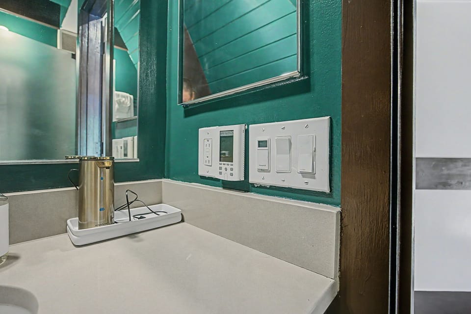 Vibrant teal walls add personality to this bathroom, complete with modern climate controls and convenient outlets to keep your devices charged throughout your stay.