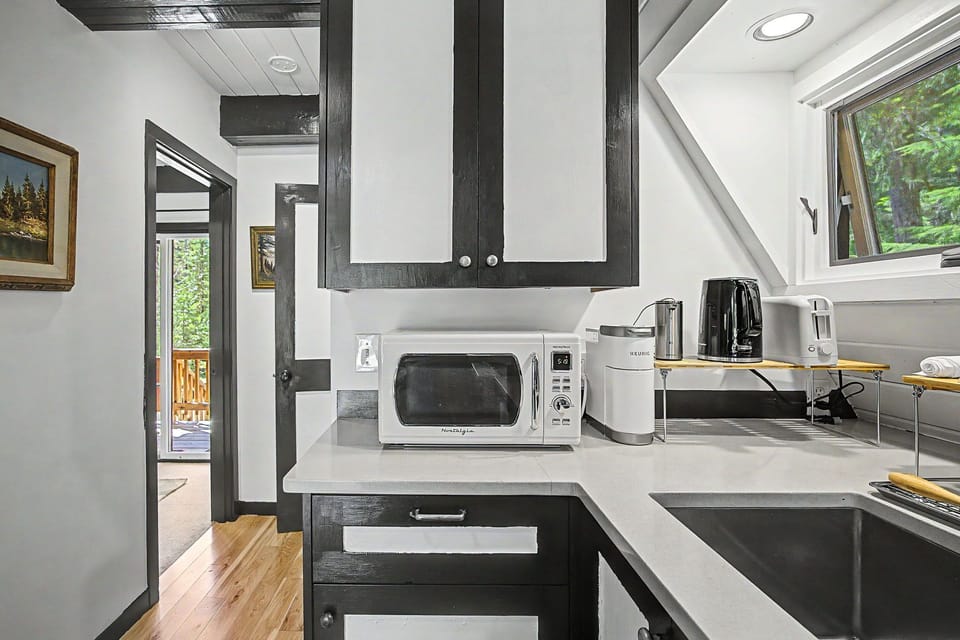 Your modern kitchen features sleek counters, a stocked microwave and coffee maker, and bright windows overlooking greenery—perfect for your morning routine or preparing a quick meal during your stay.