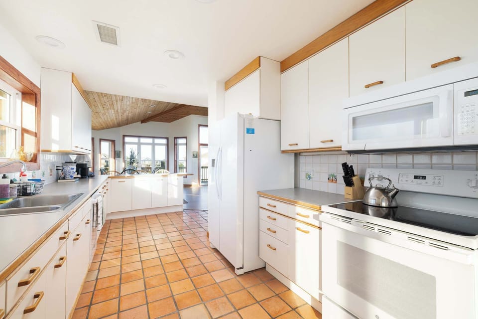 Top Level Kitchen: Fully equipped kitchen with a refrigerator, oven, microwave, dishwasher, double sink, coffee makers, and ample counter space for preparing meals with ease