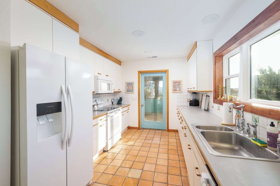 Top Level Kitchen: Fully equipped kitchen with a refrigerator, oven, microwave, dishwasher, double sink, coffee makers, and ample counter space for preparing meals with ease