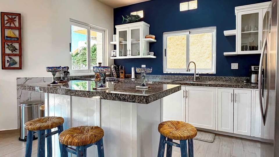 Sleek white kitchen with granite countertops and plenty of prep space.