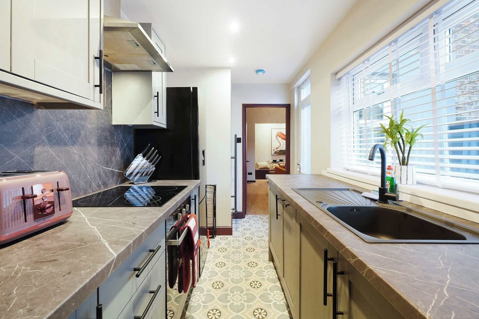 Prepare meals with ease in a practical kitchen featuring generous worktop space, a sink, and essential cooking areas for everyday use. The clean layout and simple styling provide a comfortable space for guests during short or longer stays.
