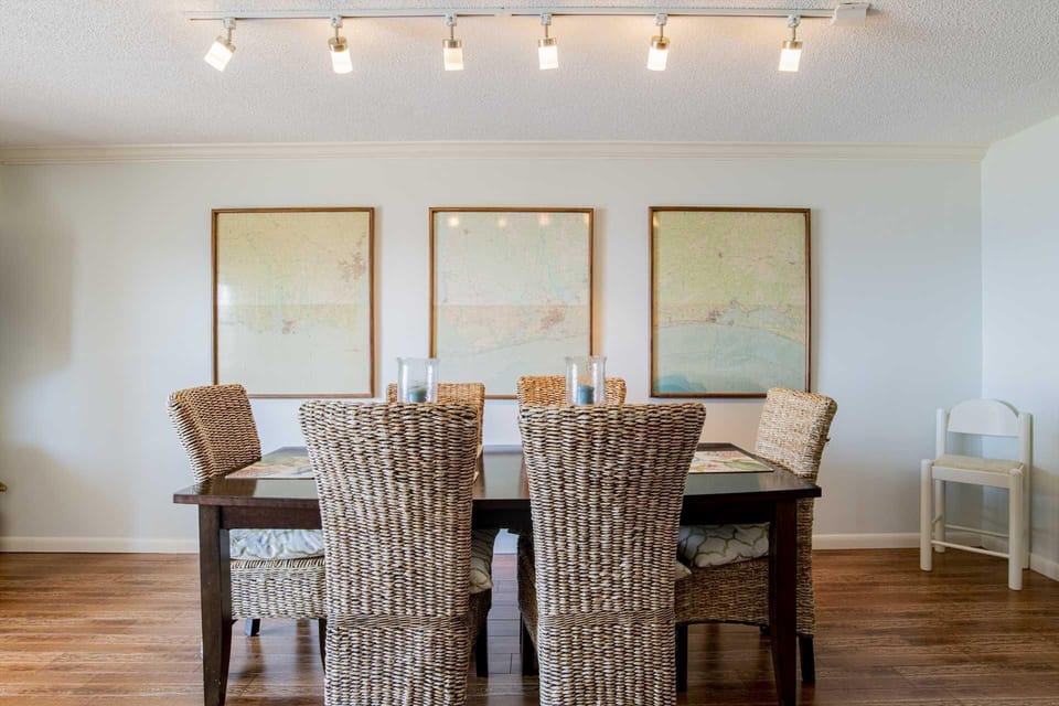 Bright dining room with woven chairs and coastal artwork