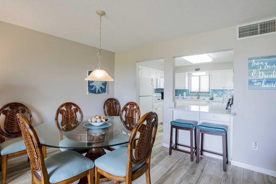 Bright dining area with glass table and breakfast bar seating