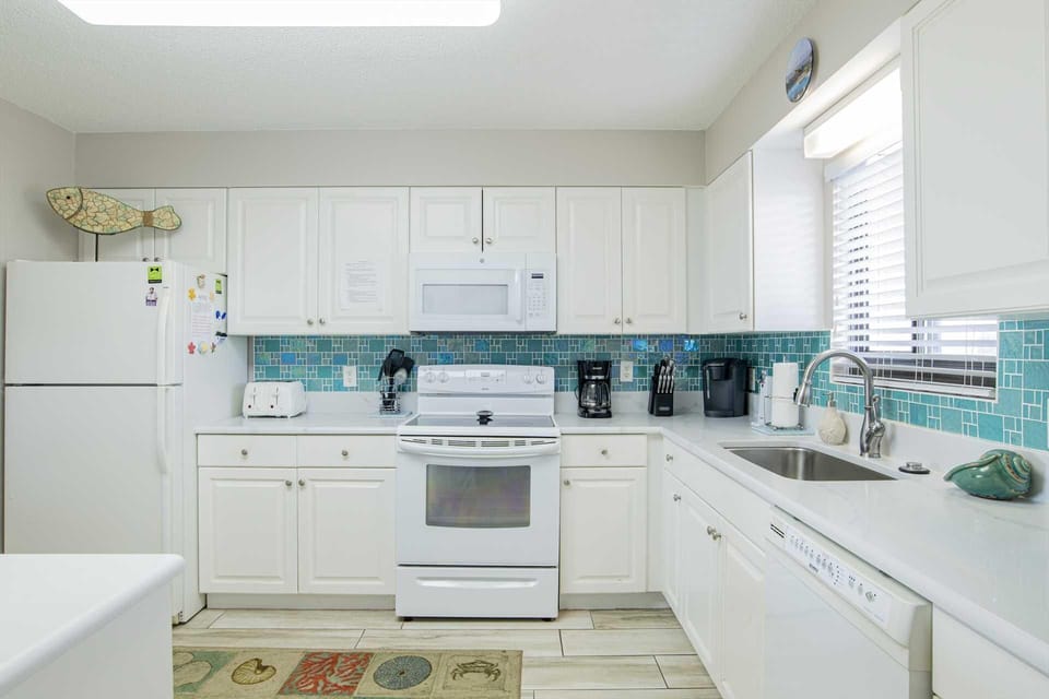 Bright, airy kitchen with vibrant turquoise backsplash and ample storage