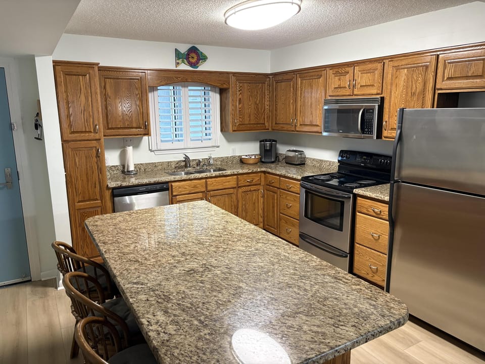 Granite countertops extend across the kitchen island and perimeter, paired with oak cabinetry and stainless steel appliances.