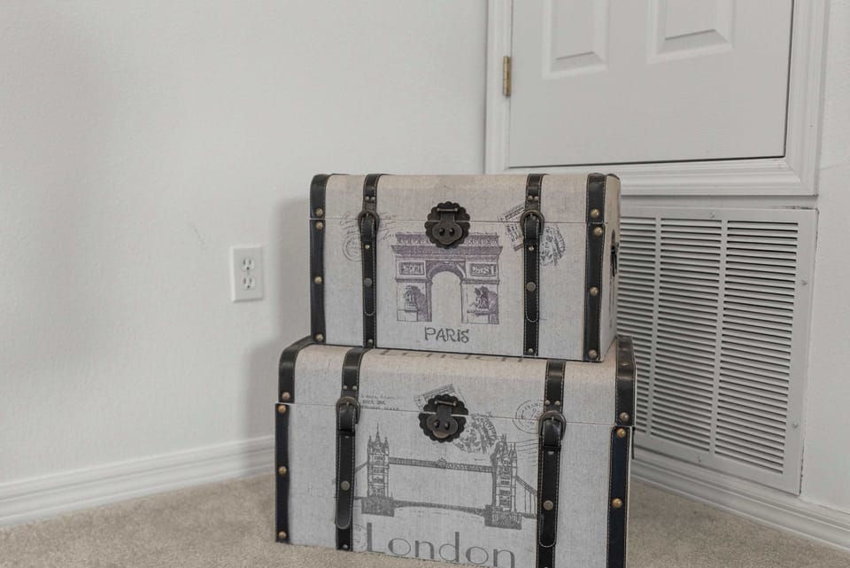Stacked vintage-style storage trunks with travel-themed prints add a unique decorative touch.