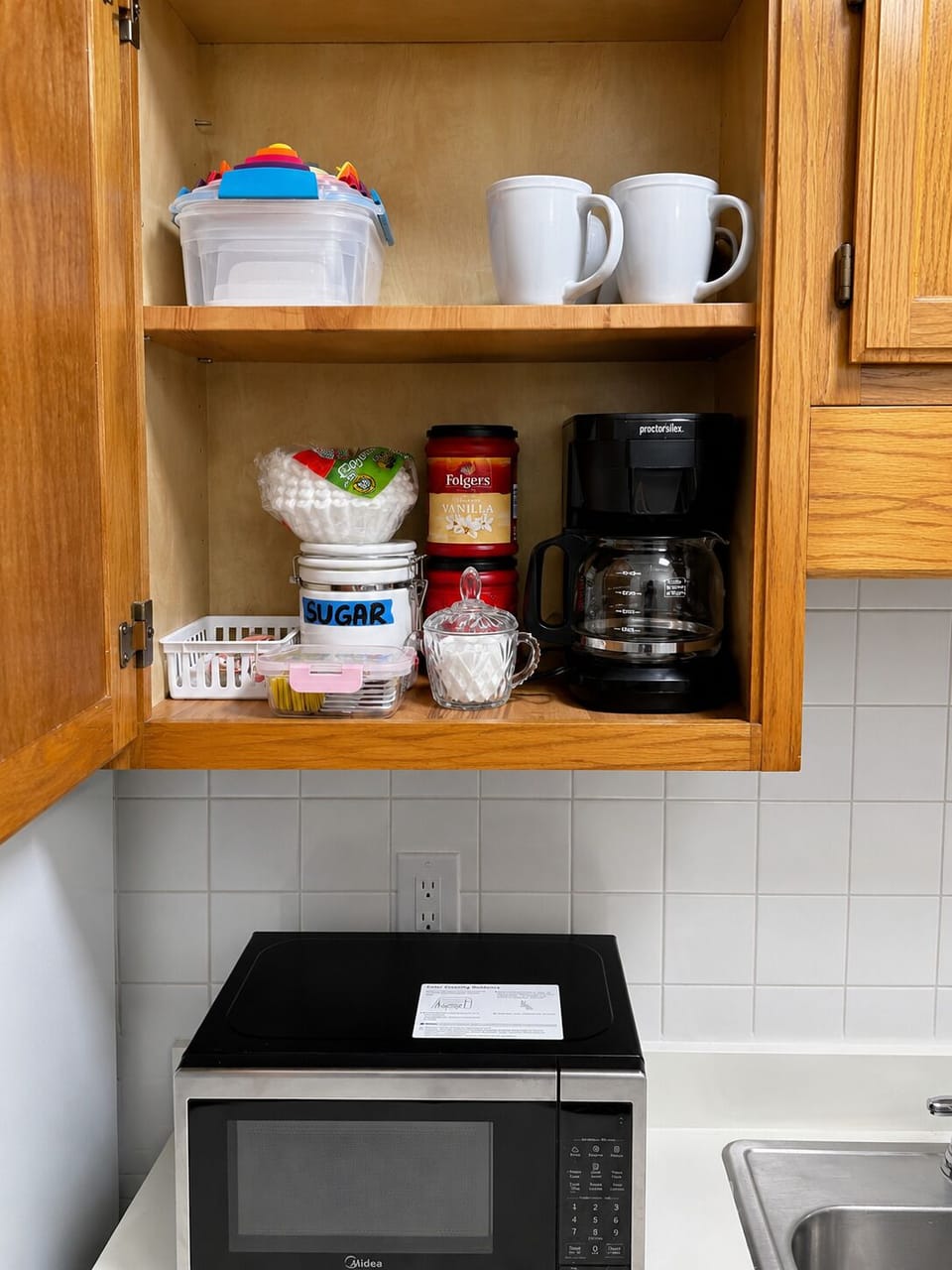 Coffee station with coffee maker, mugs, sugar, and convenient essentials