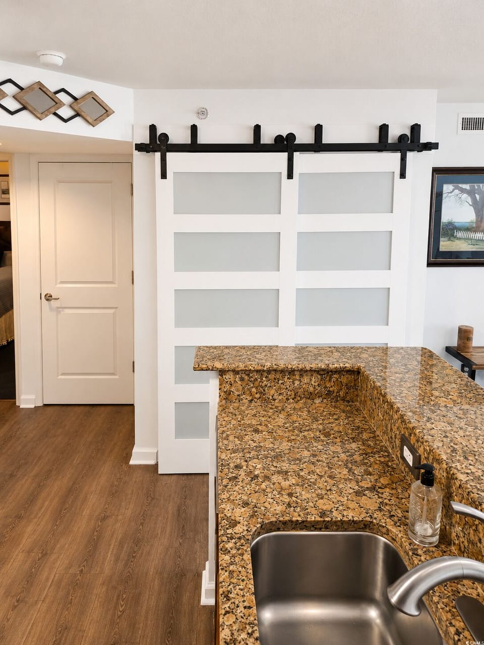 Your stylish kitchen features granite countertops, a stainless steel sink, and charming barn-style sliding doors that add character and warmth to your vacation space.