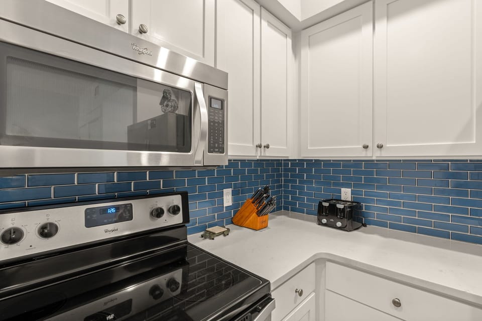 Your fully equipped kitchen features modern appliances, stylish blue subway tile backsplash, and everything you need to prepare meals at your leisure during your stay.