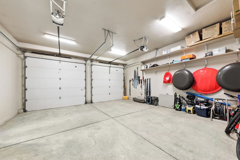 A spacious two-car garage with organized storage shelving, overhead door opener, and room for vehicles and gear—ideal for securing your belongings during your stay.