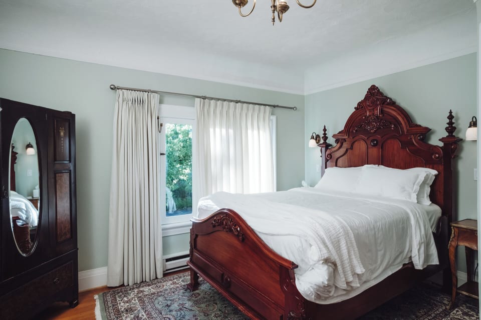 Elegant bedroom with ornate wood bed, natural light, and classic charm