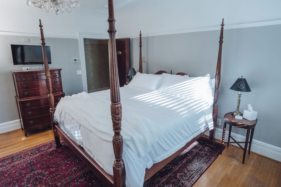 Elegant four-poster bedroom with TV, natural light, and timeless charm