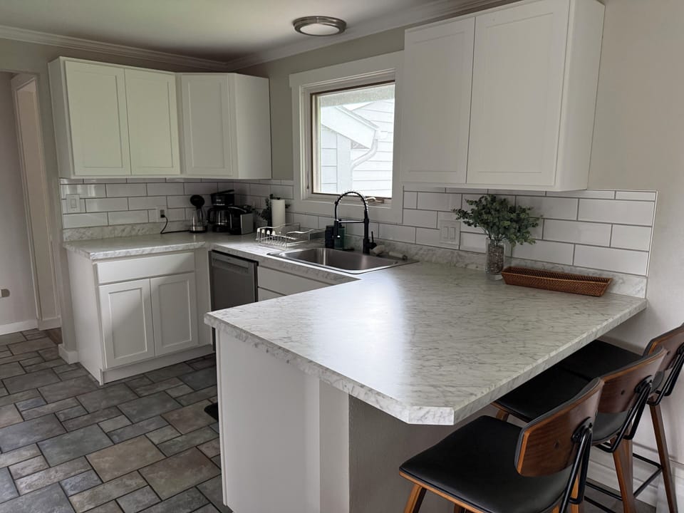 Cook and gather in the bright, fully equipped kitchen featuring modern appliances, generous counter space, and a breakfast bar for casual dining.