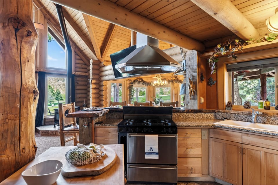Rustic log cabin kitchen with live-edge bar seating, warm wood details, and easy flow into the dining area.