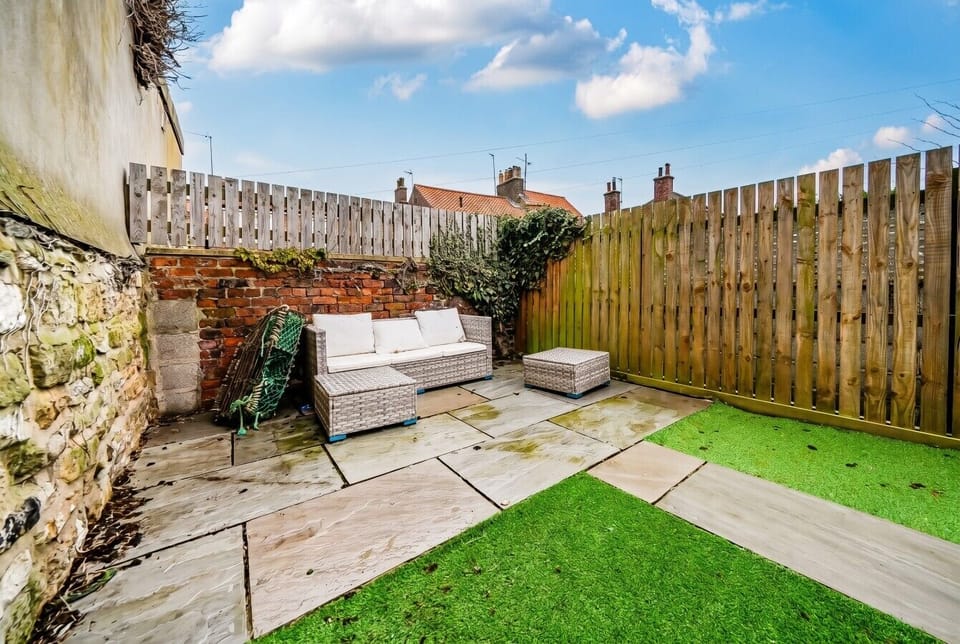 Sun-trap patio with rattan sofa, perfect for relaxing under blue skies.