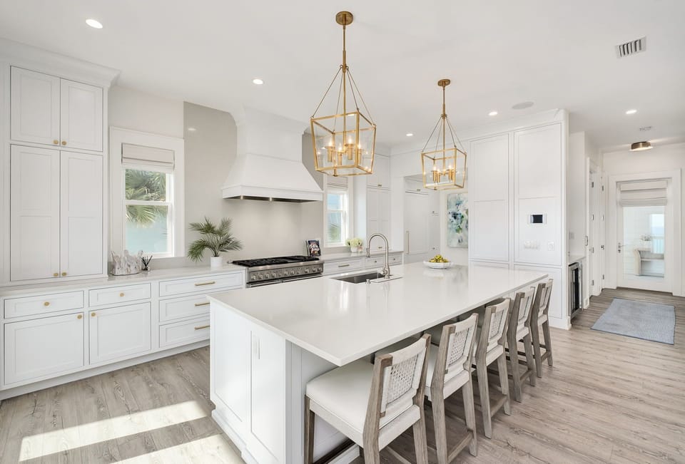 Picture yourself cooking meals in this airy, sunlit kitchen with sleek white cabinetry, gleaming countertops, and a spacious island perfect for family gatherings.