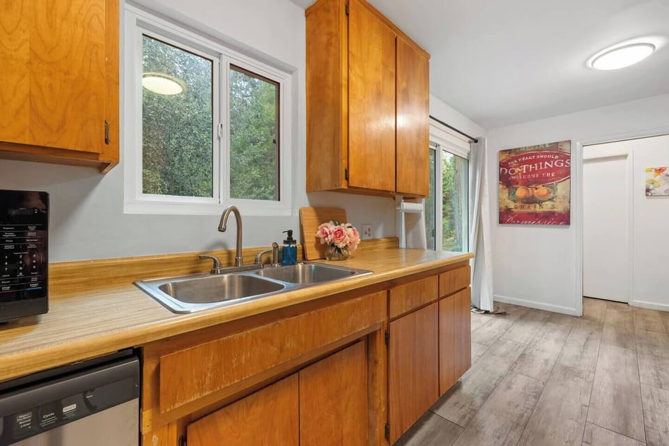 Windowed kitchen corner with double sink, warm wood cabinets, and plenty of workspace for morning coffee or cooking dinner at home.