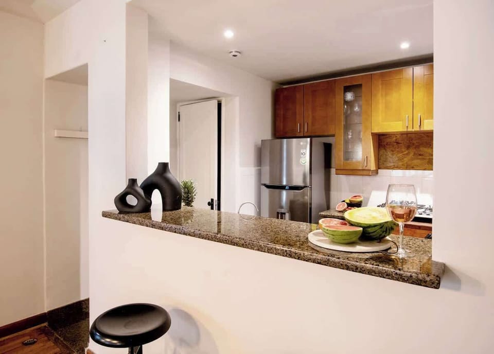 An open kitchen framed by warm wood and stone surfaces, where cooking and conversation naturally come together. The breakfast bar adds an easy, social touch, perfect for morning coffee, fresh fruit, or a relaxed glass of wine.