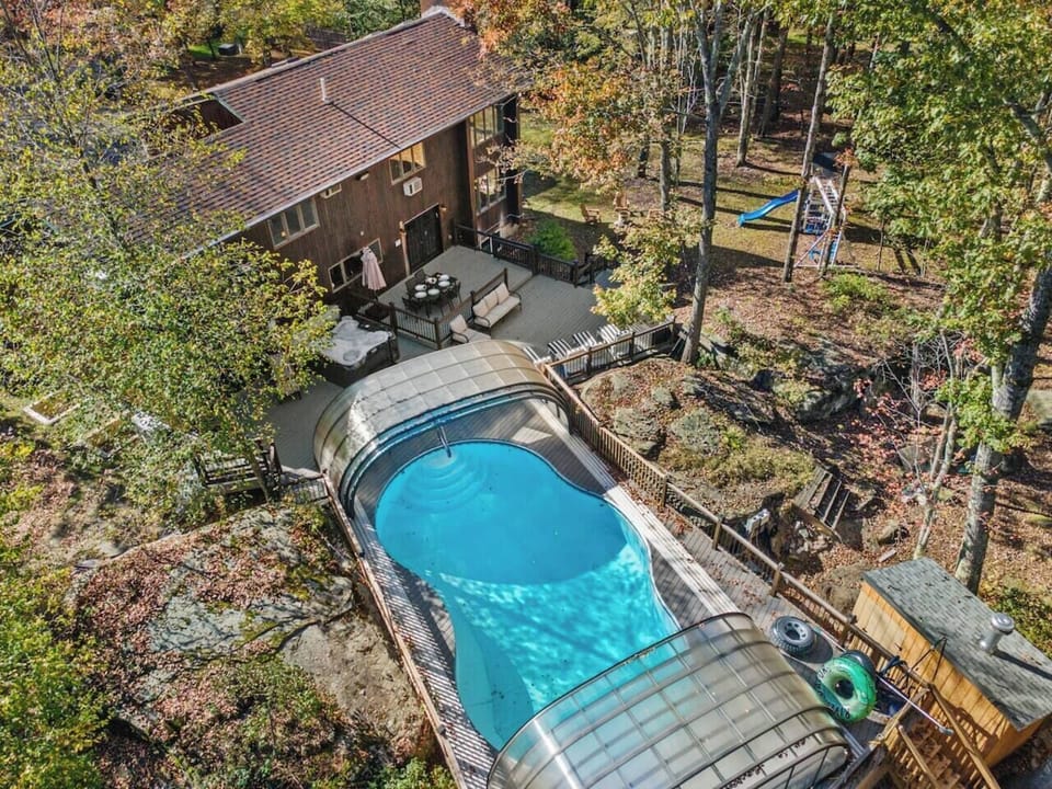 Aerial view highlighting the pool’s unique design and seamless connection to the deck and hot tub area