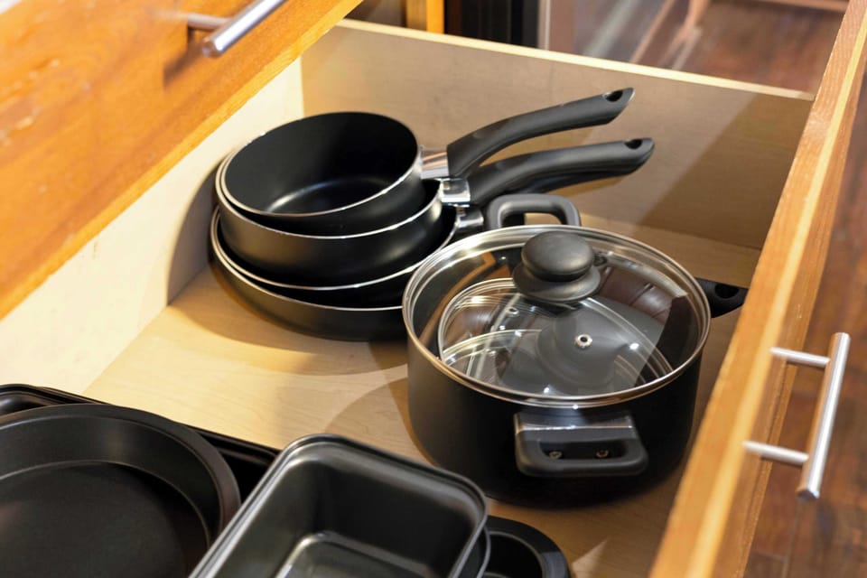 Cookware drawer stocked with pots, pans, and a baking sheet for full meal prep.