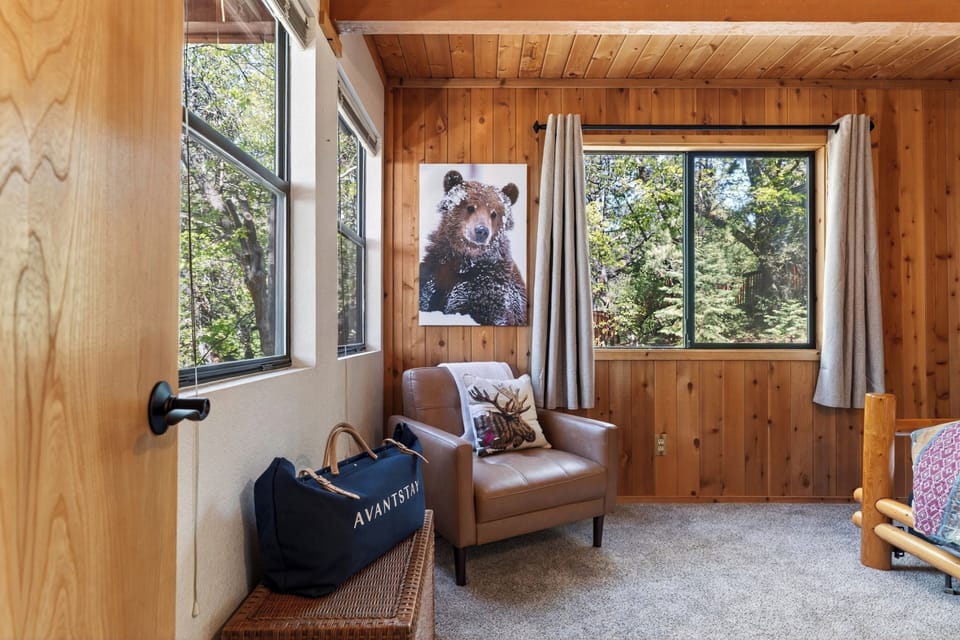 A cozy reading corner featuring a comfortable leather armchair and a large picture window overlooking the trees.