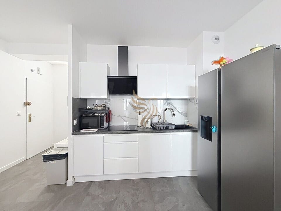 Le matin, préparez votre café sur le plan sombre pendant que la crédence marbrée capte la lumière. Le grand frigo inox garde tout frais: une cuisine pensée pour des séjours pratiques et chaleureux.