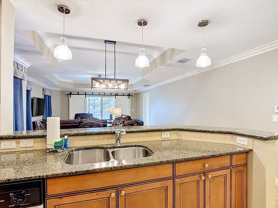 Open kitchen and breakfast bar with granite countertops, modern lighting, and plenty of space for gathering.