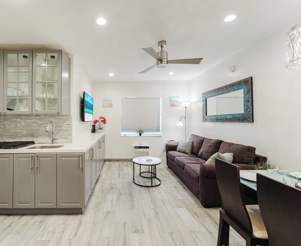 Bright, open-concept living space with a comfortable sofa, smart TV, and dining table for four—perfect for relaxing after a day at South Beach.