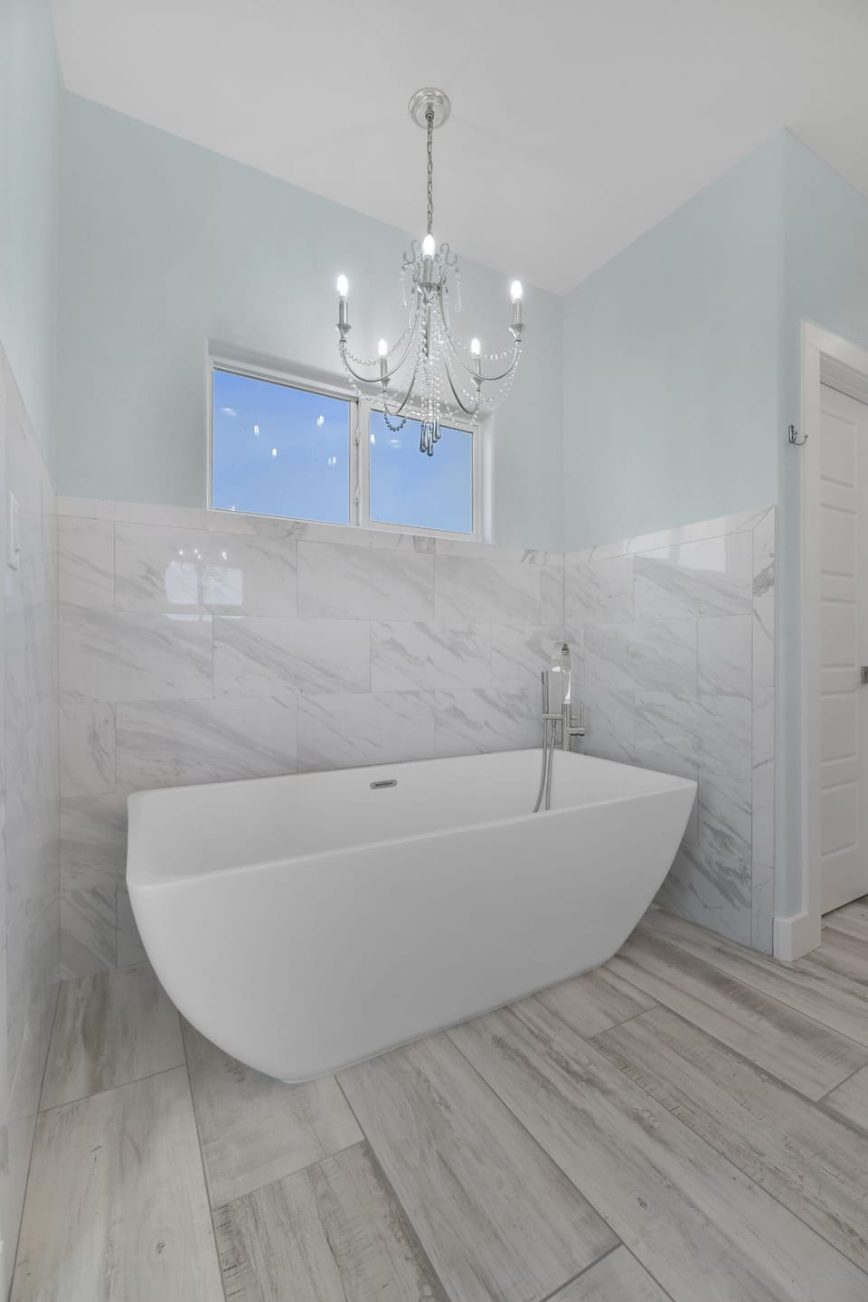 Spa Retreat: Bright bath with soaking tub and elegant chandelier for indulgence!