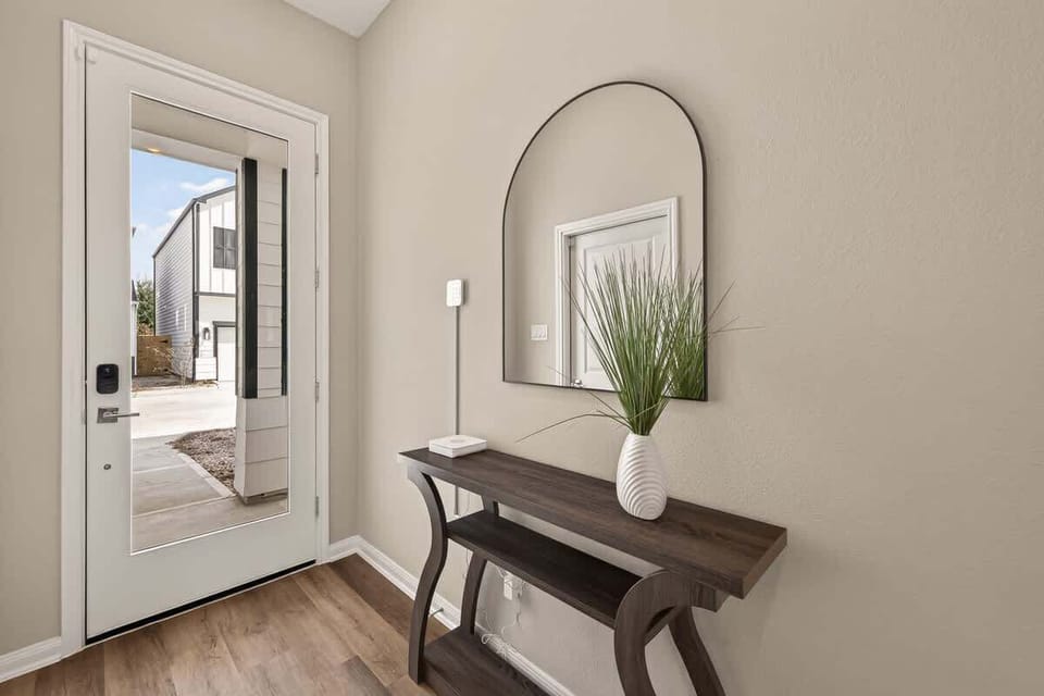 Bright and airy foyer featuring a stylish entryway console, arched mirror, and warm hardwood-style flooring.
