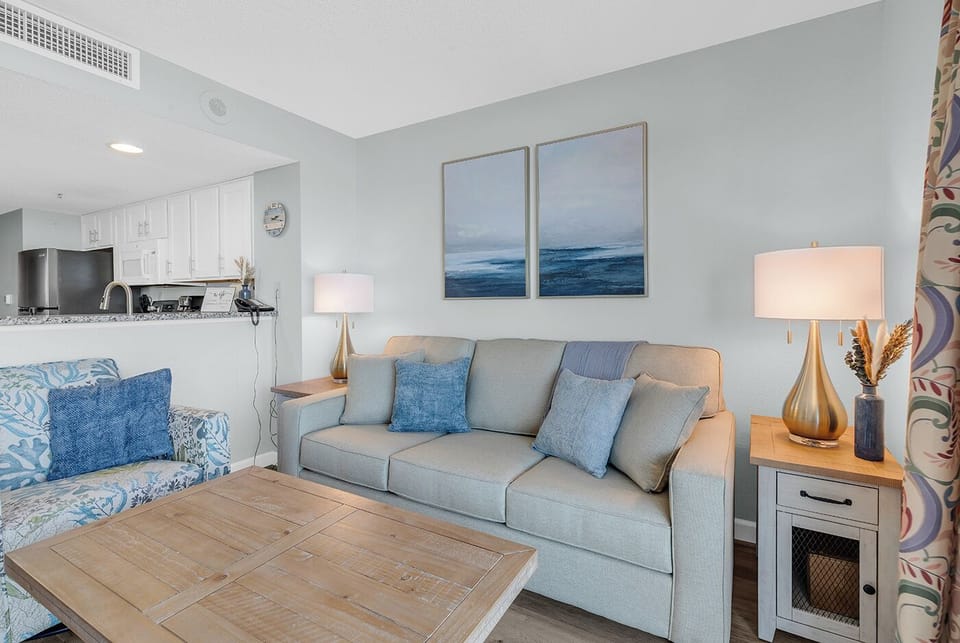 Bright coastal living room with comfy seating and open kitchen access