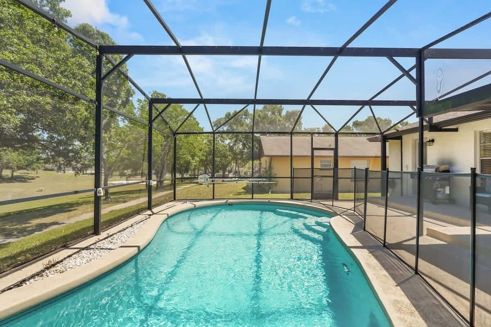     Spacious screened-in pool area featuring heated water, LED evening lighting, and panoramic views of the scenic community park, baseball diamond, and soccer fields in Kissimmee.
