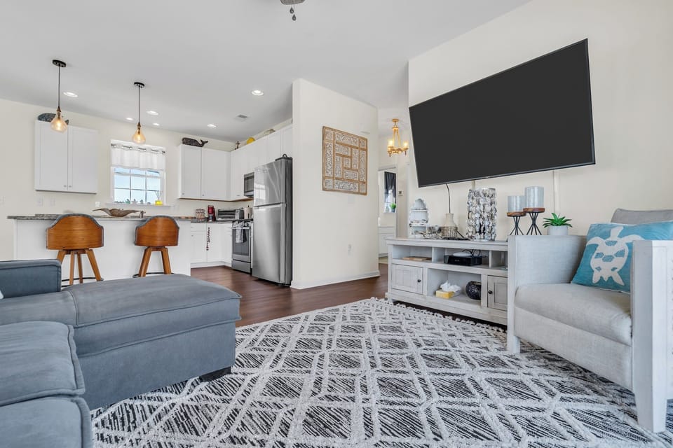 Bright open living room with modern kitchen, breakfast bar & large TV