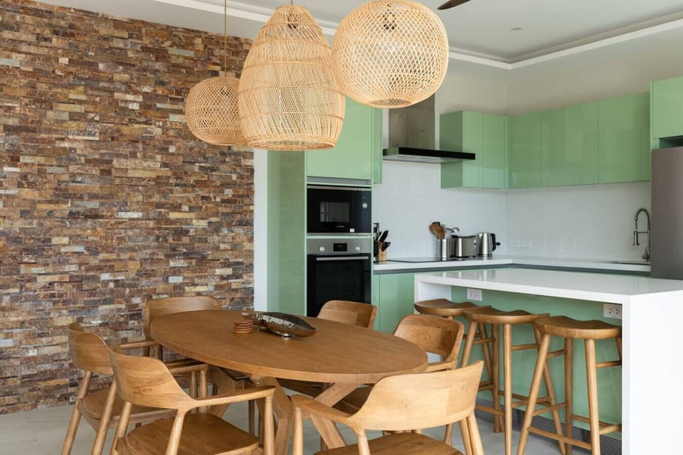 Indoor dining nook with stone feature wall and rattan pendants