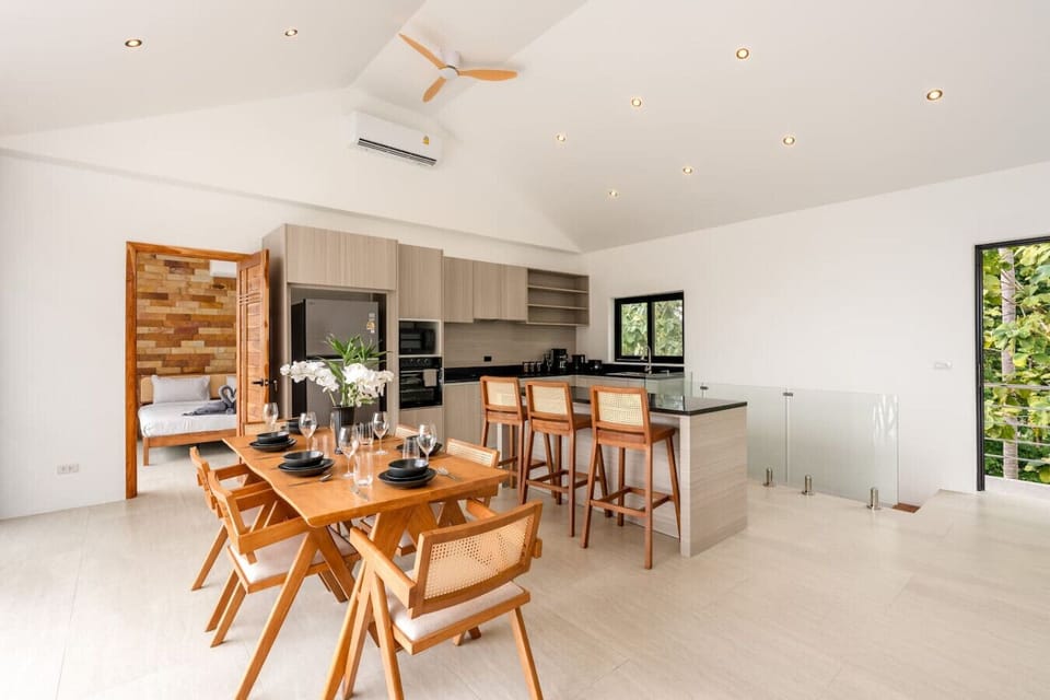 Tropical outdoor dining area with wooden table and pendant lighting at Sunrise Hill Villa