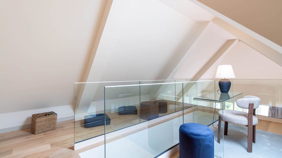 Cosy mezzanine lounge with glass railing, soft seating, and a dedicated desk area under beautiful vaulted ceilings. #Lounge #Relax