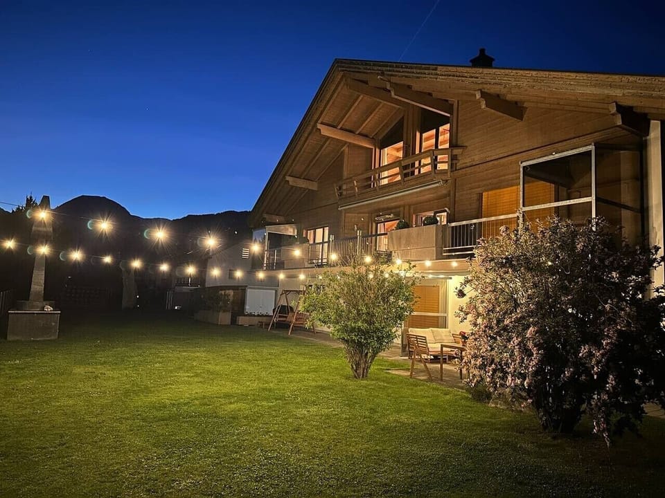 Private garden at night — glowing lights, peaceful lawn and easy ground-floor access for relaxed Swiss Alps evenings.