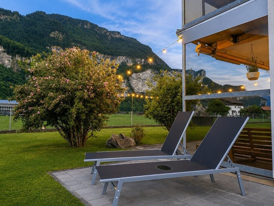 Garden sunbeds at dusk — unwind with mountain views, open green space and a calm alpine setting beside Manor 2.