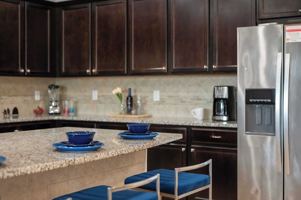 Kitchen counter detail w/ dark cabinetry & stainless steel fridge for easy entertaining.
